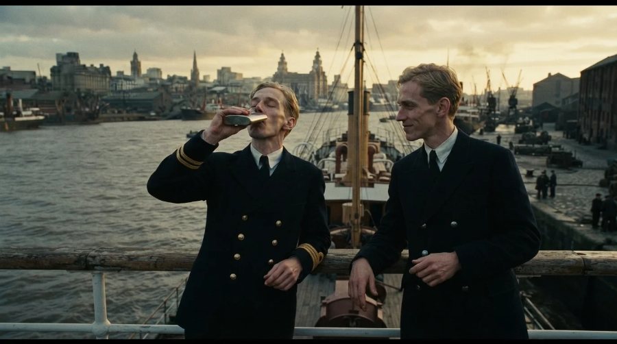 Two young ship&rsquo;s officers on deck by the same waterfront, one drinking from a flask